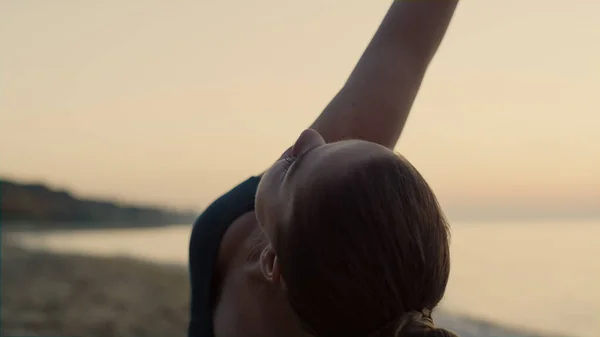 身材苗条的女运动员在练习三角裤时 一只手靠得很近 夏天的傍晚 一个体态魁梧的女人站在沙滩上练瑜伽 在外面做胡萝卜素的柔韧女孩 — 图库照片
