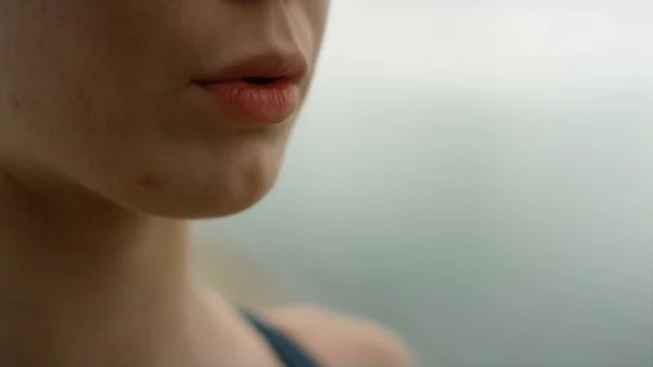 Unknown girl inhaling exhaling practicing yoga on nature close up. Young serene woman meditating on sea beach cloudy day. Closeup open mouth sportswoman making exercises outdoor. Harmony concept.