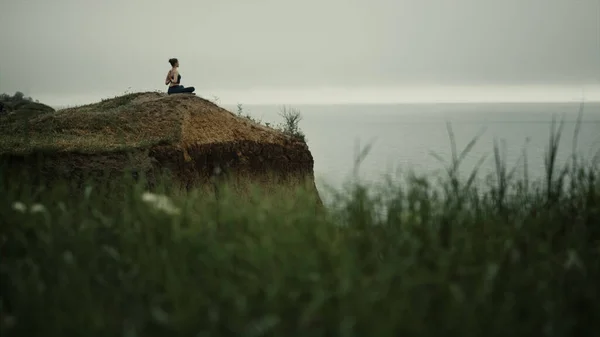 在山顶上锻炼的瑜伽女子的美丽的远景 一个安静的女孩坐在荷花上沉思 摆出阴郁的姿势 女运动员在海滩山上放松瑜伽姿势 运动健康生活方式 — 图库照片