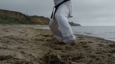 Kumsala ayak basıp karate antrenmanı yapan adam bulutlu havayı yakından takip ediyor. Tanınmayan sporcu deniz kıyısında antrenman yapıyor. Sakin okyanus dalgalarını yıkadı. Çıplak ayaklı sporcu dışarıda tekvando yapıyor..