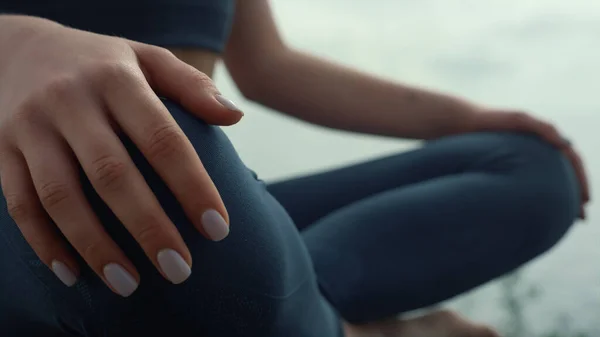 Woman hands lying feet in lotus pose close up. Unknown sporty girl doing yoga sitting on beach hilltop outdoors. Athlete lady meditate in sportswear summer morning. Calmness harmony concept.