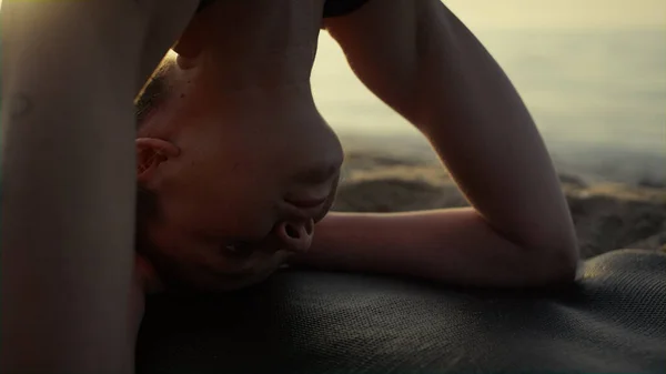 紧紧围绕着瑜伽女孩站在头顶训练平衡 迷人的女运动员面临着在沙滩上练习瑜伽的挑战 一个坚强的女人在日落时立正 体育生活方式概念 — 图库照片
