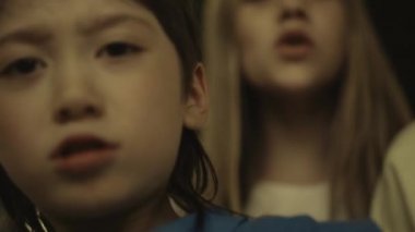 Closeup diverse pupils shouting on conflict victim standing school hall together. Aggressive asian boy pushing unknown outcast. Angry classmates insulting helpless schoolchild. Teens cruelty concept.
