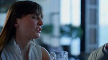 Closeup businesswoman drinking whiskey in bar. Ceo person resting and talking at formal dinner hotel lounge. Rich leader spending time with unknown colleague in fancy panoramic window restaurant
