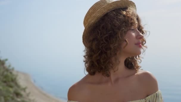 매력적 곱슬곱슬 아가씨가 아래서 얼굴을 감싸고 있습니다 아름다운 해변에 지푸라기 — 비디오