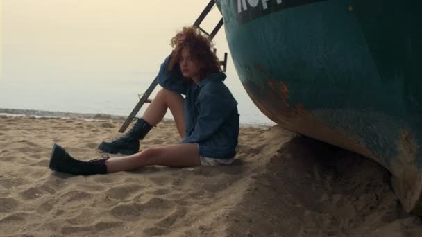 Сумна Молода Жінка Сидить Пляжі Біля Старого Човна Хмарно Вранці — стокове відео
