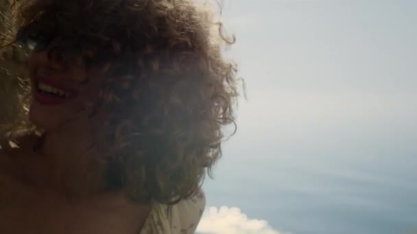 Gülen Kız Mavi Okyanusun Önünde Otururken Kafasını Sallıyor Kıvırcık Bukleler — Stok video