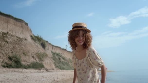 바다에서 곱슬곱슬 매력적 미소짓는 여름날 밀짚모자를 양지바른 해변에서 재미있게 것이다 — 비디오