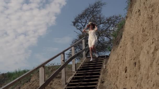 Mujer Sonriente Enérgica Corriendo Abajo Playa Arena Sosteniendo Sombrero Paja — Vídeo de stock