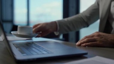 CEO elleri okyanus manzaralı yakın çekimde kahveyi bitiriyor. Bilinmeyen yönetici kontrat belgelerini kontrol ediyor. Tanınmayan zengin iş adamı lezzetli espresso molasından sonra mali raporları gözden geçirdi 