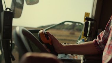 Çiftçi elleri hasat aracını yakından sürüyor. Güneş ışığında traktör operatörü makineleri kontrol ediyor. Tanınmayan adam sürücüsü, modern otomatikleştirilmiş sistemi kırsal kesimden ayarla. Tarım endüstrisi kavramı.