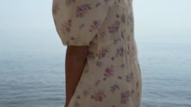 Deniz suyunda zıplayan, elinde hasır şapkayla dönen sevimli bir kadın. Sahilde zıplayan çiçekli elbiseler giyen mutlu kız. Tasasız genç bayan güzel yaz sahillerinde iyi eğlenceler..