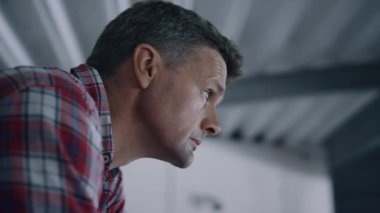 Farm employee controlling work milking system in mechanical modern barn close up. Focused professional man inspecting milk production process on ranch. Business owner looking on cowshed from balkon.