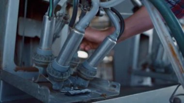 Çiftçi, otomatikleştirilmiş mandıra çiftliğinde sağma sistemi ekipmanlarını kontrol ediyor. Bilinmeyen tarım mühendisi modern süt üretim cihazlarını modern ahırda inceler. Teknolojik makine kavramı