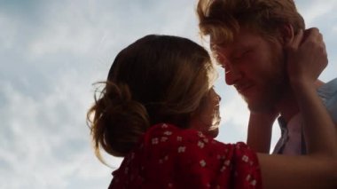 Closeup affectionate couple cuddle together outside. Young lovers enjoy sun cloudy sky nature. Silhouettes girlfriend boyfriend caress touch hair on summer holiday. Honeymoon love marriage concept.
