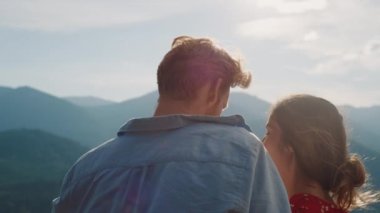 Fun couple enjoy mountains view outdoors. Close up happy lovers cuddle on nature vacation. Back view husband wife look beautiful landscape on sunny day outside. Summer vacation honeymoon love concept.
