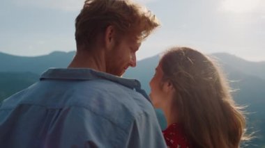 Smiling couple look mountains landscape view. Happy lovers enjoy hike outdoors back view. Close up young people spend time on romantic date. Relaxed family rest on summer vacation. Marriage concept.
