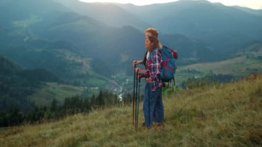Sırt çantalı çiftler manzara dağ manzarasının tadını çıkarırlar. İki yürüyüşçü yeşil tepenin doğasında rahatlar. Sportif turistler güneşin doğuşuna bakarlar. Aktif yürüyüşçüler tatil maceralarında sırt çantası takarlar. Seyahat kavramı.