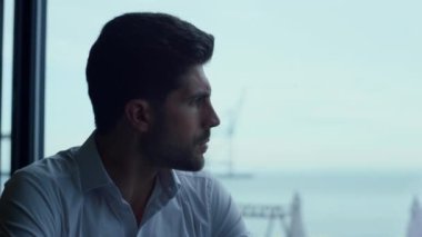 Yakışıklı maço adam panoramik restoranda tek başına vakit geçiriyor. Modern kafe portresindeki şık girişimci iş stratejisi. Kendine güvenen erkeksi yüz ifadesi, yakın plan..