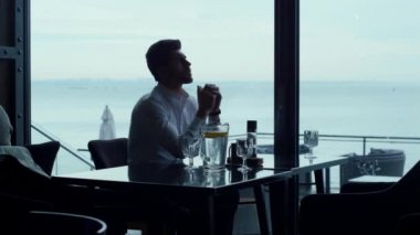 Panoramik restoranı dinlendirirken yeni iş projeleri düşünen yakışıklı bir serbest çalışan. Düşünceli girişimci silueti akşam yemeğini kafede yiyor. Endişeli iş adamı barda bekliyor..