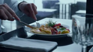 Unknown male hands cutting delicious dish closeup. Elegant businessman eating exquisite food in modern restaurant profile. Serious man enjoying tasty dinner in cozy cafe. Wealthy wellbeing concept.