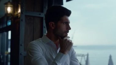 Serious businessman looking seascape resting luxury panoramic cafe alone profile. Charming manager thinking business strategy in lounge hotel bar. Focused man making decision in cozy restaurant.