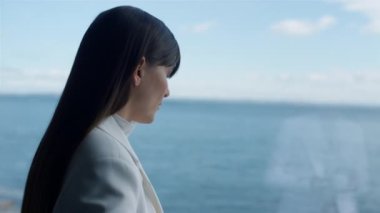 Closeup melancholic woman looking panoramic window. Serious businesswoman enjoying ocean view portrait. Thoughtful entrepreneur thinking at luxury hotel overlooking water. Business lifestyle concept 