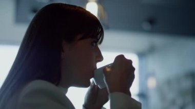 Kadın yüz dinlenme espresso yakın çekim. Rahat iş kadını silueti, koyu kafede kahve molası veriyor. İsimsiz bir lider lüks otel salonunda sıcak bir içecek yudumluyor. Tatil kavramı