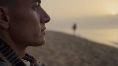 Günbatımında okyanus manzarasına bakan düşünceli bir adam. Göz kırpan hayalperest adamın portresi. Deniz kıyısında koşan mutlu bir kadın silueti. Genç çift plajda tatil yapıyor. Boş zaman konsepti 
