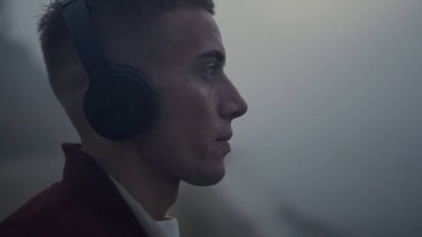 Kulaklıklı ciddi bir adam kameraya bakıyor. Kulaklıkla müzik dinleyen yalnız adam. Erkek model sabahları deniz manzarası seyrediyor. Dudaklarını ısıran düşünceli bir adamın portresi. Gençlik kavramı 