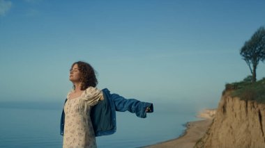 Huzurlu, güzel bir kadın boş plajda tek başına, giyinik gözlerle dikiliyor. Genç ve çekici bir kız doğanın tadını çıkararak el ele veriyor. Kıvırcık, tatlı bayan deniz kıyısında rahatlar Güzel bir sonbahar akşamı.