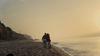 Mutlu çift birlikte eğleniyor. Sahilde eli kolu bağlı güzel bir adam var. Okyanus kıyısında yürüyen şık hippiler. Pozitif kadın ve erkek yazın günbatımının tadını çıkarıyorlar. Seyahat kavramı