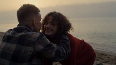 Güneşin doğuşunda deniz sahilinde sevgili bir çift. Okyanus kıyısında koşan neşeli bir kız. Mutlu sevgili kucaklaşması. Sevgi dolu bir adam bir kadını yanağından öpüyor. Romantik konsept