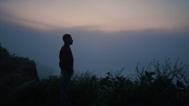 Üzgün adam silueti sabah dağın tepesinde duruyor. Gündoğumunda sonbahar manzarası seyreden yalnız bir adam. Sakin bir erkek sisli manzaranın tadını çıkarıyor. Hayatı düşünen bunalımlı bir adam. Sakin doğa sahnesi