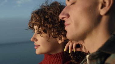 Sahilde son gün batımının tadını çıkaran genç bir çift. Yakından gülümseyen bir kadın ve kamerada poz veren gözleri kapalı bir adam. Deniz kıyısında rahatlayan hayalperest kız ve erkek portresi. Yaşam tarzı kavramı