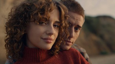 Kameraya bakan gülümseyen çiftin portresi. Sahilde poz veren neşeli kadın ve erkek yüzleri. Sevgi dolu adam arkadan sarılan kız. Erkek arkadaş ve kız arkadaş duygularını ifade ediyor. Aşk konsepti 