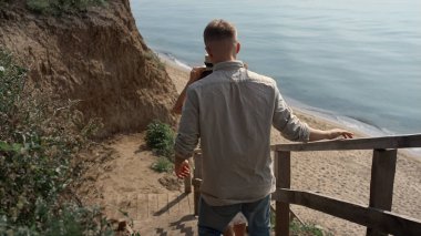 Genç mutlu çift merdivenlerden aşağıya güzel sahil manzarasına iniyor. Merdiven boşluğunda yürüyen neşeli, sevimli bir çift. Şık bir kadın güneşli yaz doğasında çekici bir adamla dinlenirken eğleniyor..