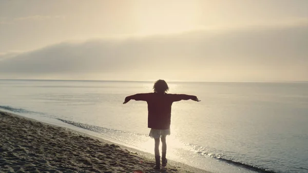 幸せな女の子は日の出にビーチで休暇を過ごす 積極的な女性の手を上げる 勝利を祝う女性 感情的な女性の海辺で回っている 朝の海の景色 自由の概念 — ストック写真