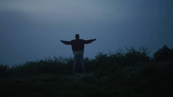 孤独的家伙走在雾蒙蒙的田野里 后视镜上的男子举起双手在空中 积极的男性模特儿在户外享受自由 清静的人 早晨凝视着山水 神秘的雾气 — 图库照片