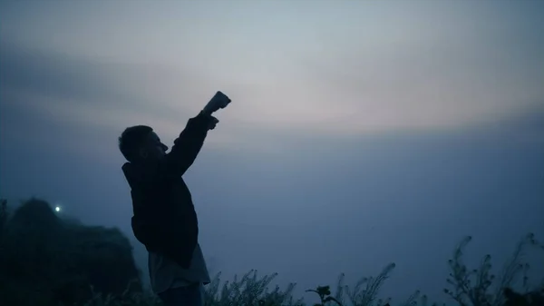 若い男が日の出に山の端に立っている 興奮した男が空中で手を挙げている 霧の多い山の中で自由を感じる幸せな男性のヒップスター 屋外で成功を祝う積極的な男 勝者のコンセプト — ストック写真