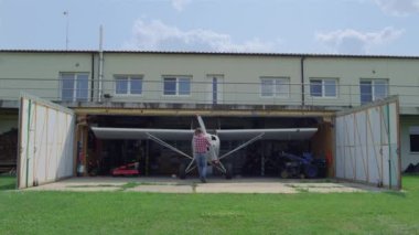 Havacı, kırsal havalimanındaki hangarın içinde uçak pervanesini tamir ediyor. Ulaşım başlamadan önce küçük beyaz uçakları tamir eden profesyonel havacılık mühendisi. Uçan hobi konsepti. 