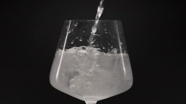 Köpüklü su, buzlu cam döküyor. Ağır çekimde yakın çekim. Temiz bardakta buz küpleriyle kaynayan sıvı. Hava damlaları, maden suyu ve şarap kadehinin içinde hareket eder. Organik kokteyl konsepti