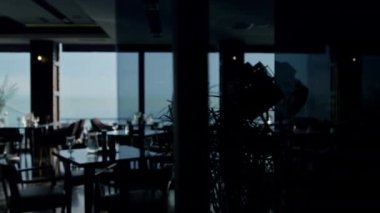 Served lunch tables in spacious stylish cafeteria with beautiful sea view. Comfortable hotel restaurant dining hall background. Modern panoramic sky bar dark interior. Luxury dinner concept.