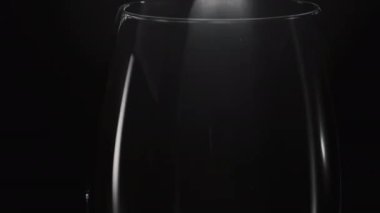 Buz küpü boş bardağa yakın çekim yapar. Buz bloğu, şeffaf şarap kadehini ağır çekimde fırlatıyor. Görünüm makro siyah arkaplanı kuruluyor. İçecek ve kokteyl hazırlama konsepti