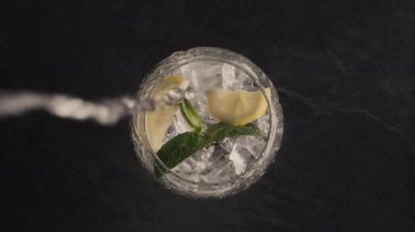 Buzlu limonlu naneli kokteyl yakın plan. Soğuk su jeti naneli ve limonlu olsun. Kıvırcık yaz içkisi siyahın üstünde. Lezzetli arınma içeceği. Kokteyl süreci konsepti yapılıyor