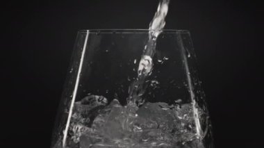 Buzlu su, şarap kadehini yakınlaştırıyor. Şeffaf camlarda buz küpleri olan berrak bir sıvı. Hava damlaları siyah arkaplan olan mineral su. Canlandırıcı kokteyl konsepti hazırlanıyor