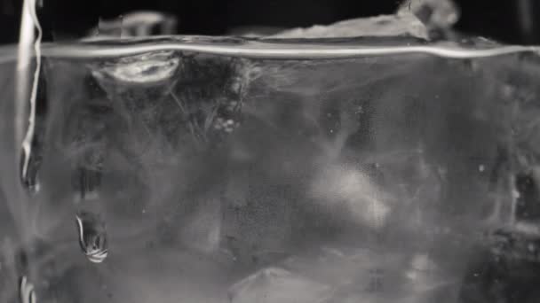 结冰的立方体闪烁着水的近距离慢动作 滴滴流下透明的玻璃与苏打水饮料宏景 冰清澈的液体酒杯 离子纯矿物鸡尾酒概念 — 图库视频影像