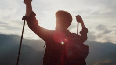 Closeup euphoric hiker celebrate win raise hands in mountains nature. Emotional traveler reach peak on landscape hill. Satisfied ginger guy scream on extreme trip journey. Success freedom concept.