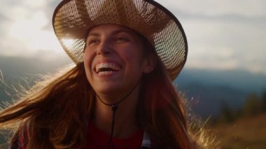 Smiling woman look sunset on mountains hill. Portrait of playful girl laugh on nature view. Excited model posing enjoy holiday outdoors. Joyful traveler spend summer vacation. Happy leisure concept.