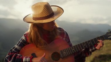 Closeup talented woman play acoustic guitar outdoors. Professional guitarist perform in mountains. Artistic girl hold musical instrument compose song on green hill nature. Music hobby leisure concept.